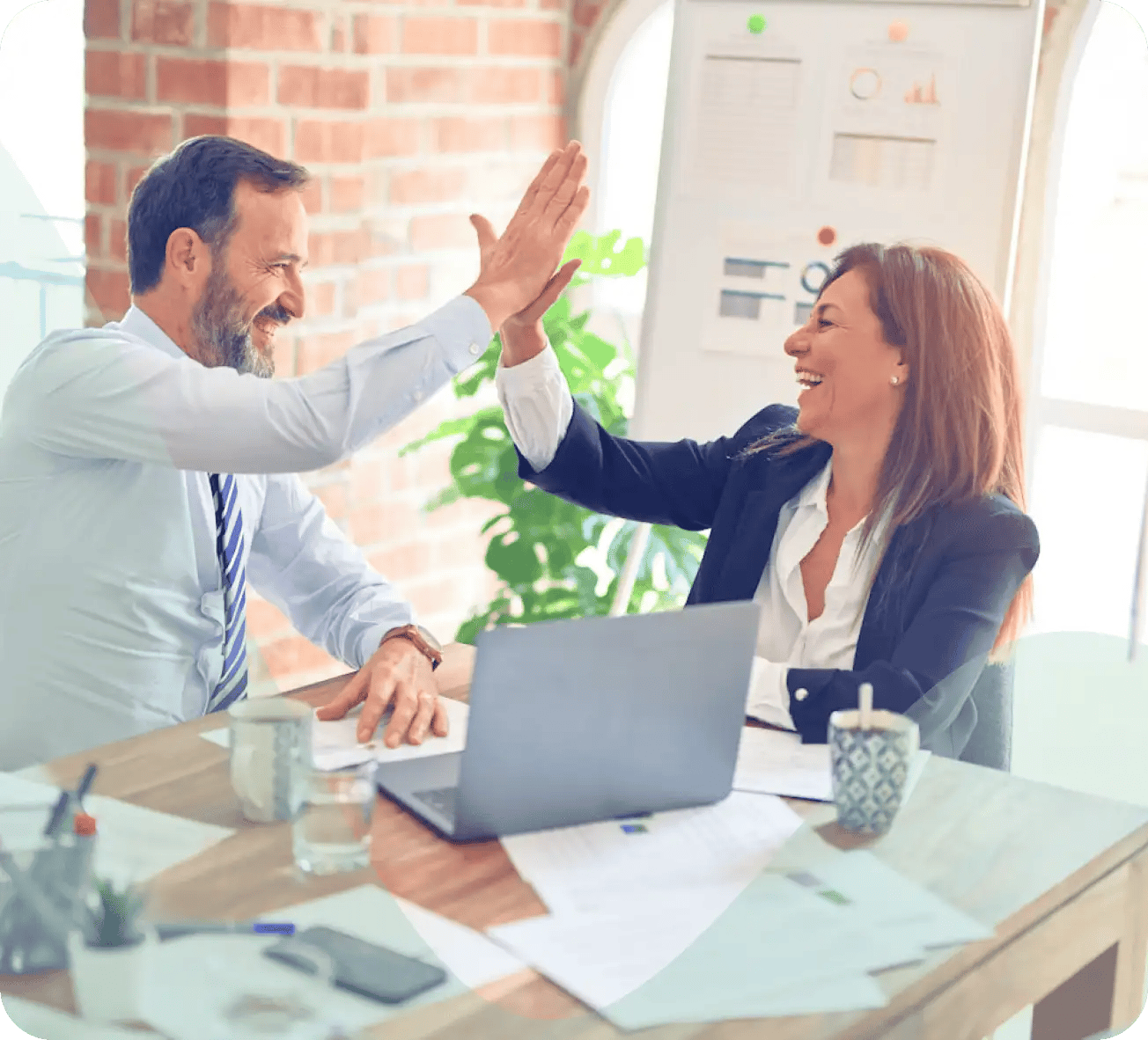 Coworkers high fiving in office